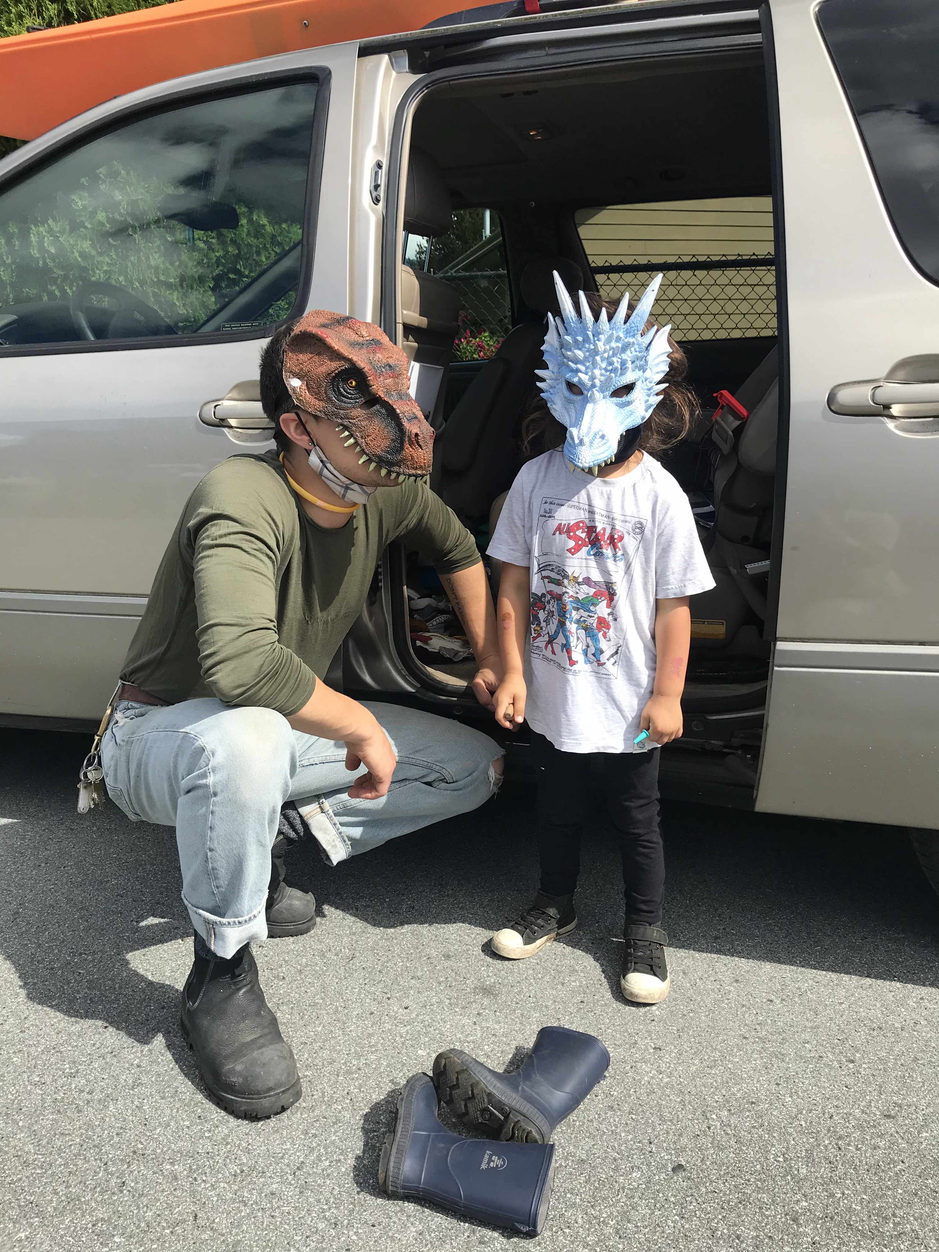 Conor and Rowan posing in front of Conor's van. They are both wearing dinosaur masks