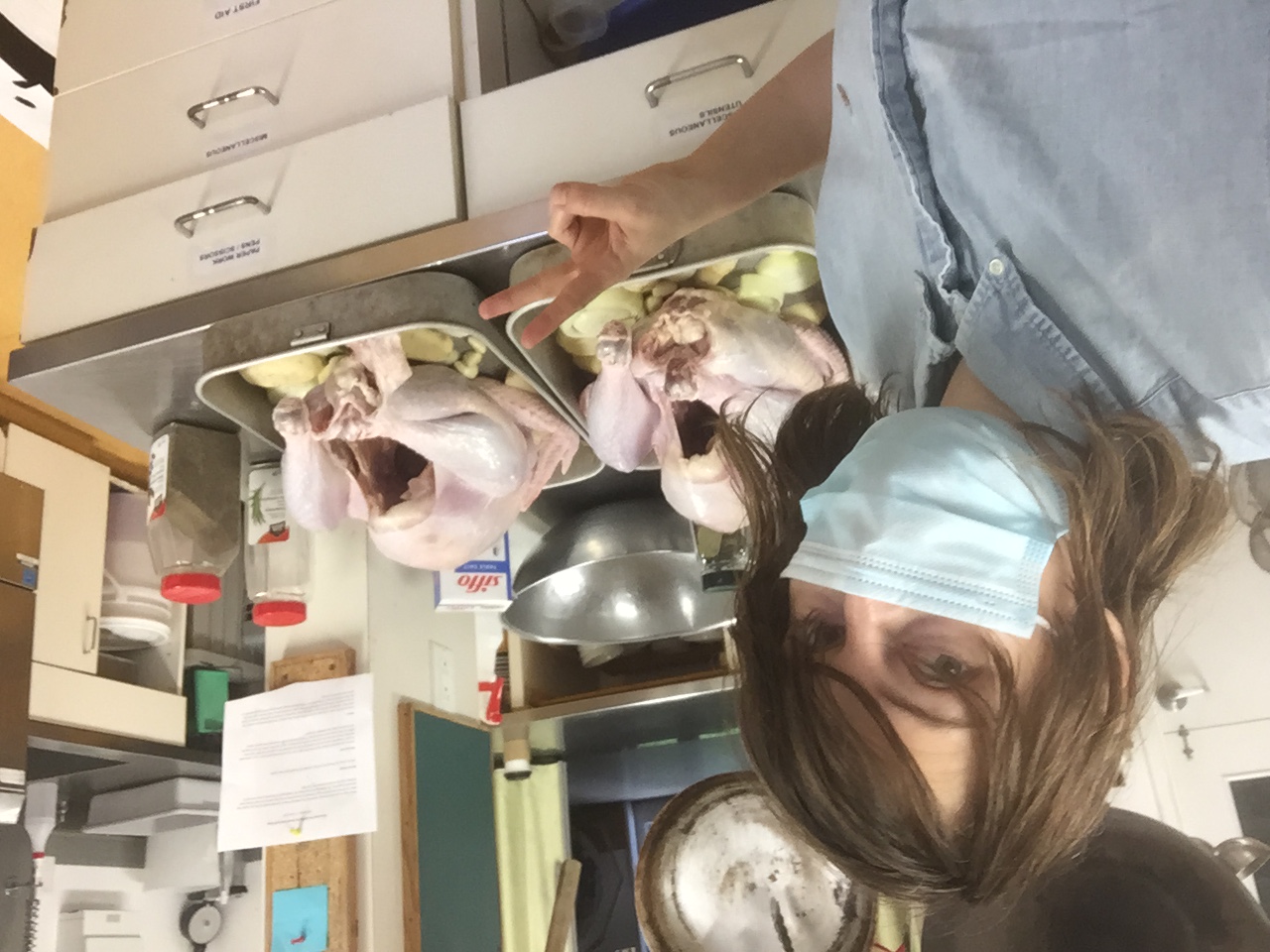 Vivienne posing in front of two full turkeys that have been seasoned prepped with fruit underneath.