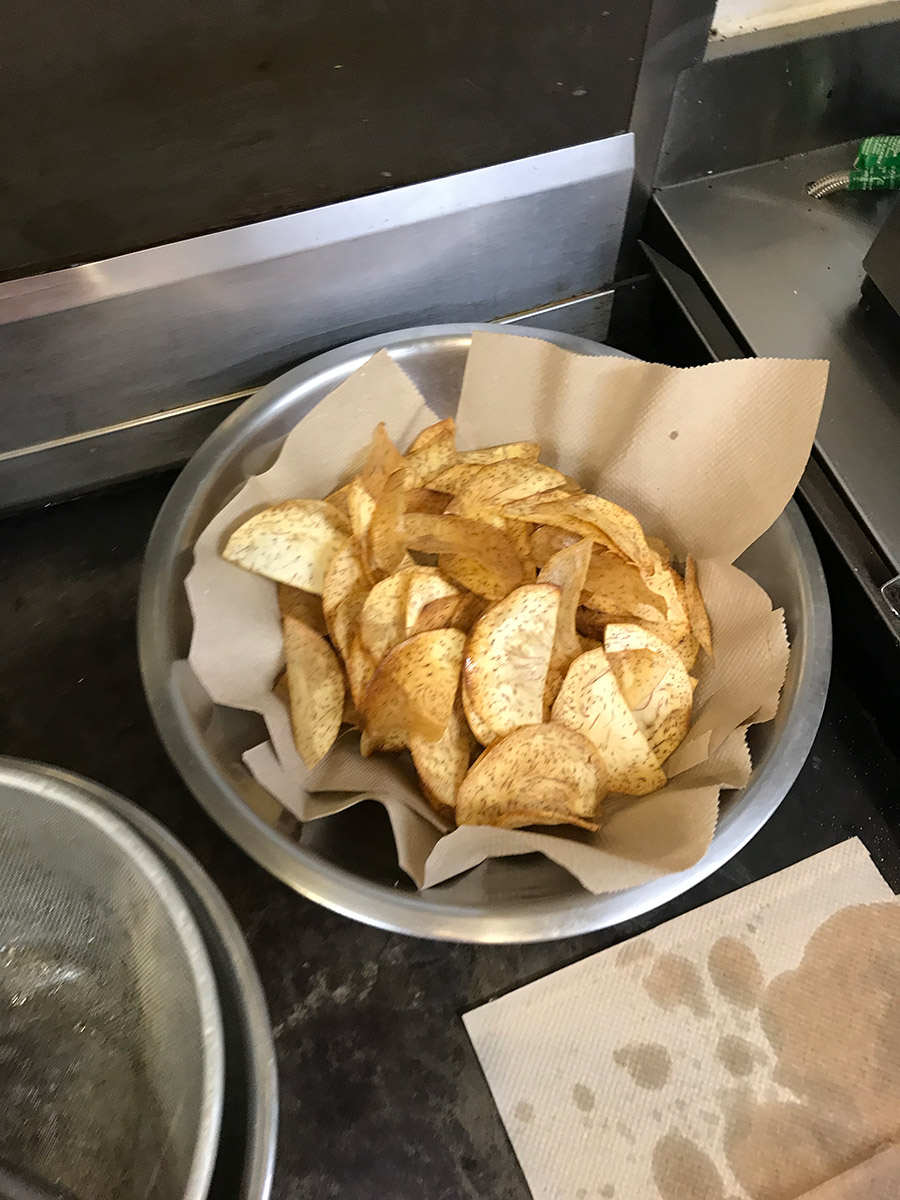 fried taro chips resting in a bowl with paper towls absorbing the grease. about the quantity of a large bag of chips.