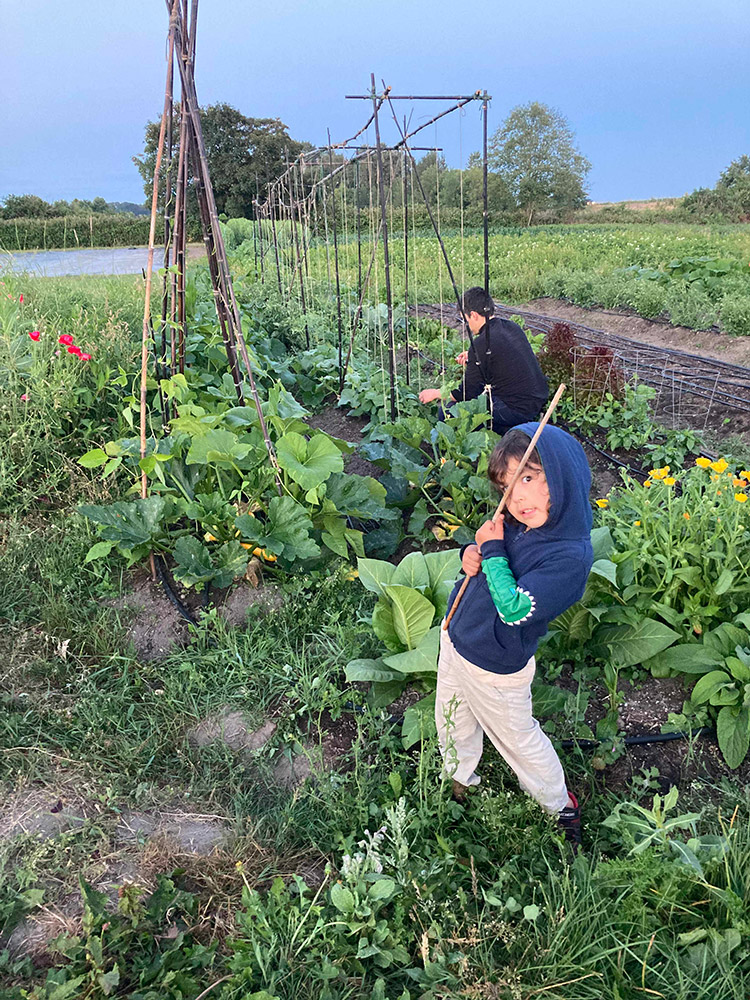 Rowan posing  in front of a garden plot that Conor is tending to