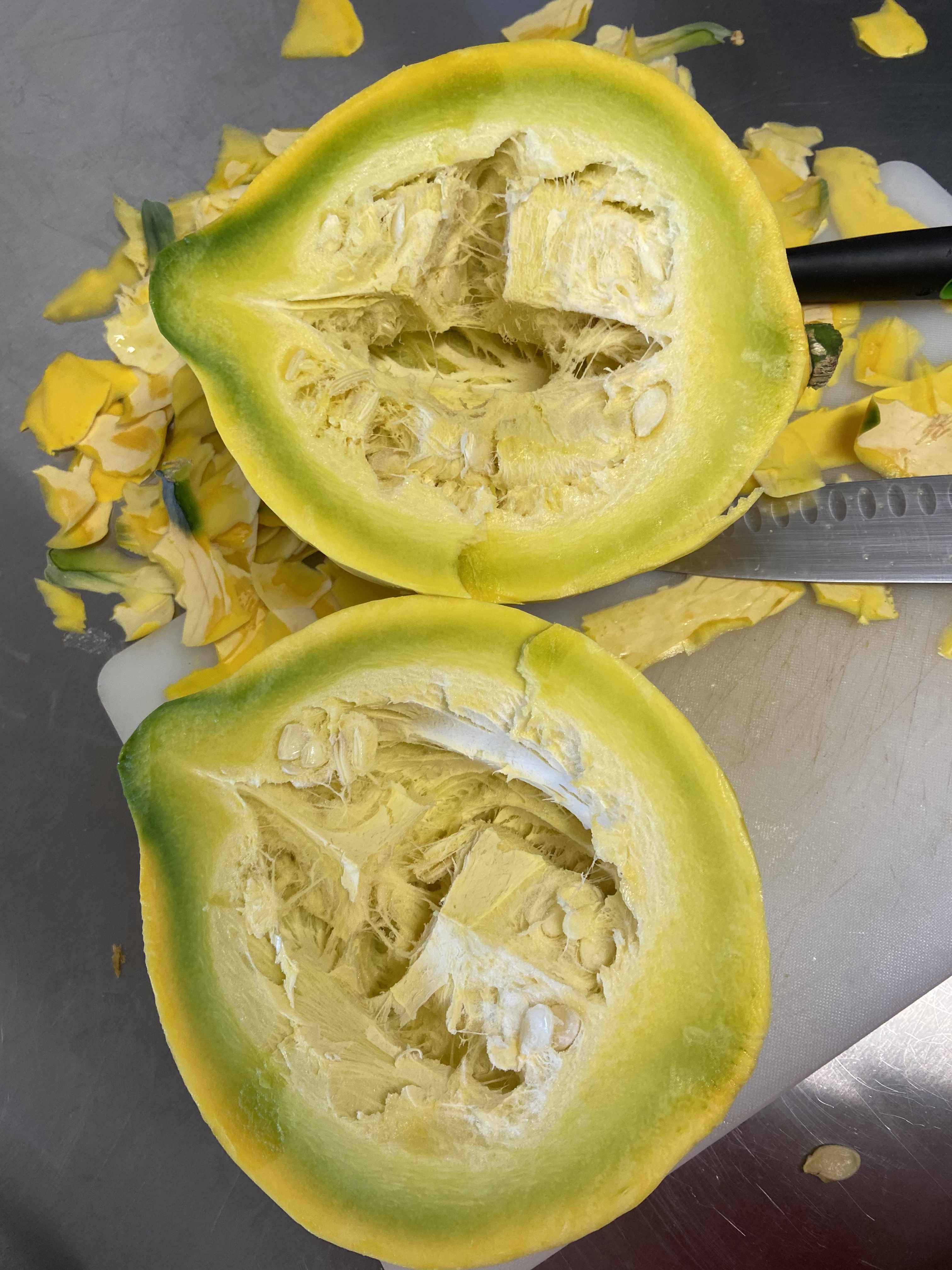 A squash that has been cut in half. Inside it has a soft pulpy center followed by seeds and an inch of flesh