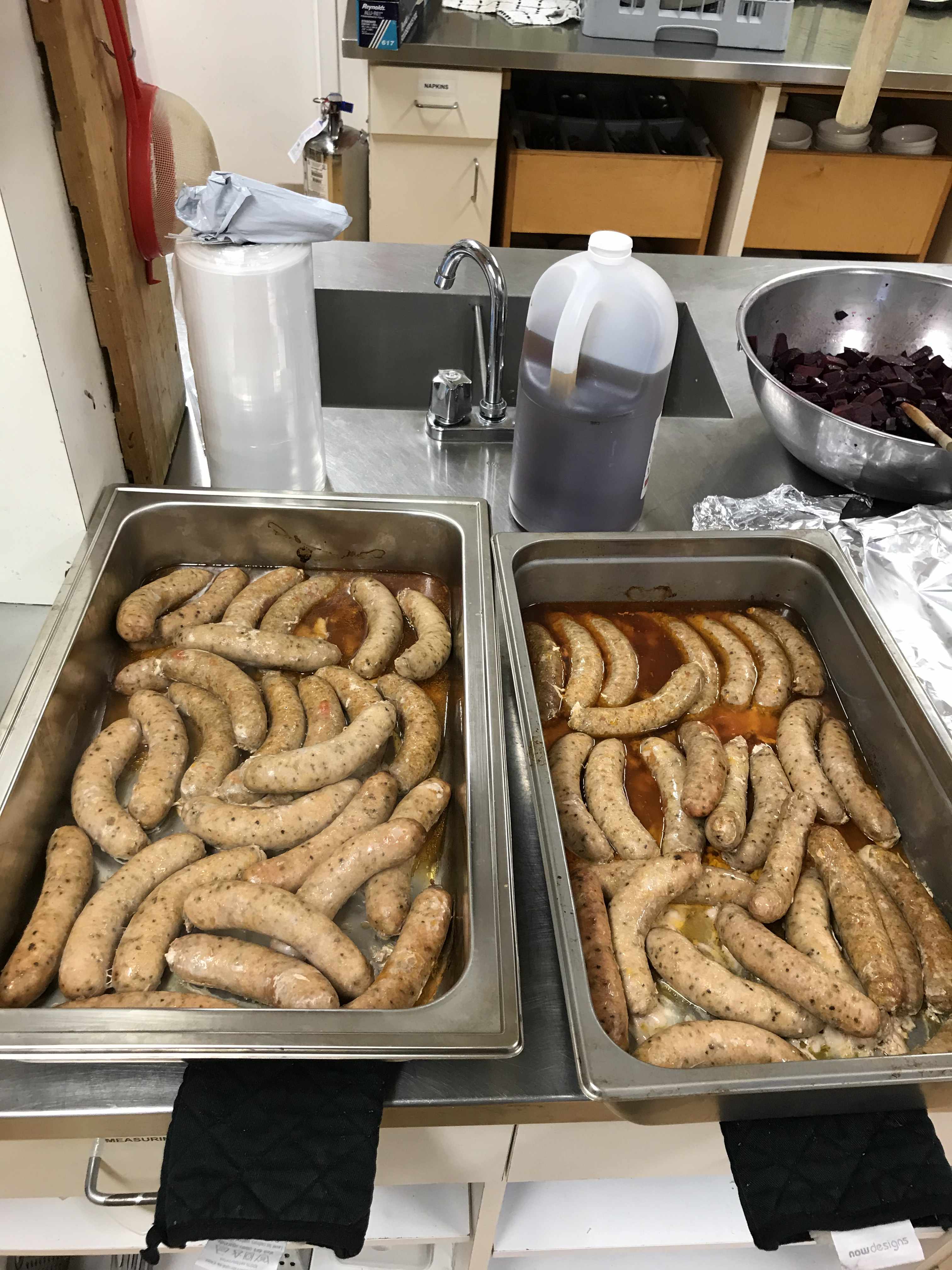 2 hotel pans of sauces cooking in their own fat, about 30 sausages per tray