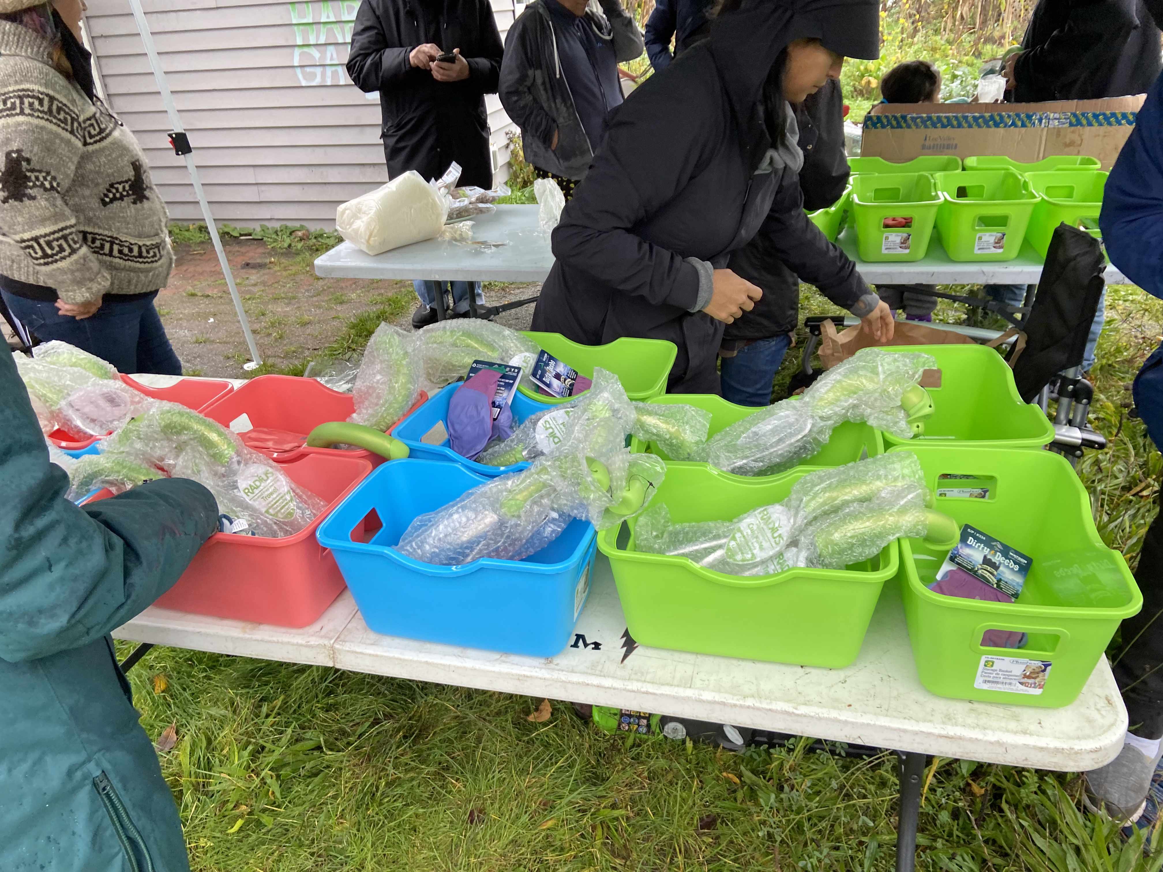 view of a dozen rectangular plastic buckets with wrapped garden equipment inside